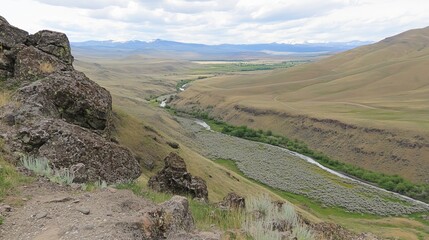 Panoramic view of a river valley winding through a dry, mountainous landscape, with rocky outcrops and sparse vegetation