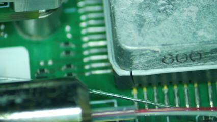 Close up of electronic chip on green circuit board with metal components and fine wires showing...