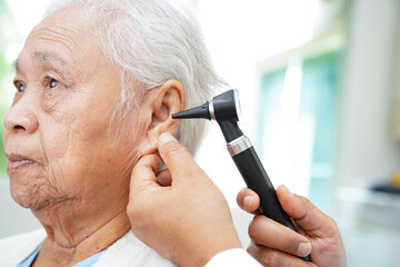 Otolaryngologist or ENT physician doctor examining senior patient ear with otoscope, hearing loss problem.