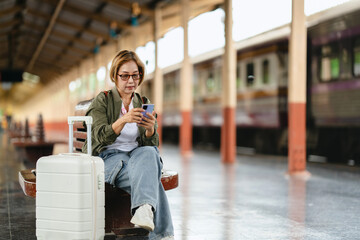 Mature woman using smartphone while waiting at train station