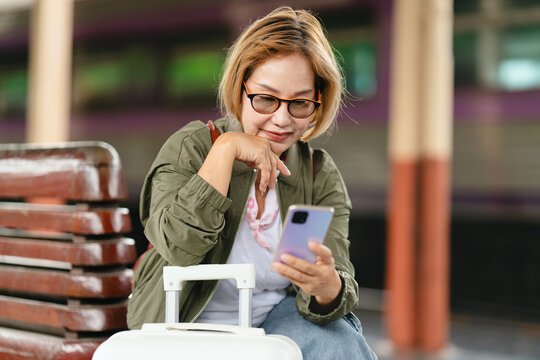 Mature female traveler using smartphone at train platform