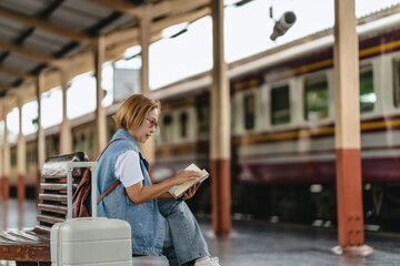 Woman traveler with suitcase at train station awaiting journey