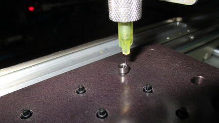 Automated machine with precision focus dispensing yellow glue from nozzle during an industrial...