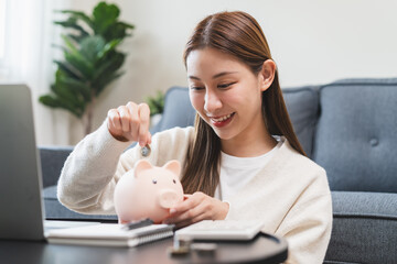 Close-up hand of young woman putting  a coin into piggy bank.