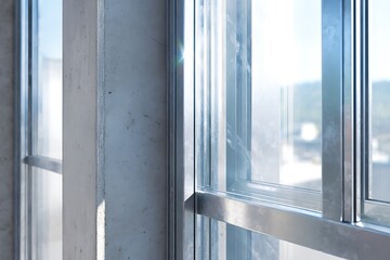 Obraz premium Aluminum Window Frames Being Fitted Into A Concrete Wall. Glass Panels Partially Installed, With Protective Film Visible. Light Should Reflect Naturally On Metallic Surfa