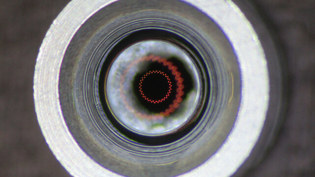 Mysterious macro closeup of an optic lens inside metal tube. This abstract camera technology shows futuristic view with an intriguing red circle and precise focus