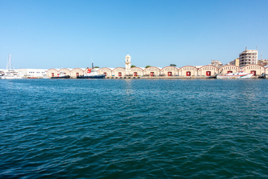 Gandia, Valencia, Spain - June 23, 2025: Clock Tower and port sheds, vaulted warehouses called Tinglados, in the port of Gand&iacute;a. Gand&iacute;a is the capital of La Safor County, in the Valencian Community.