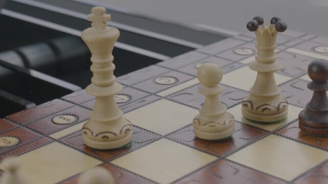 the hand of a person moving a chess king piece on a board