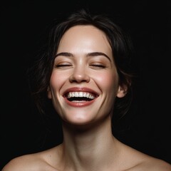 A portrait of a woman, her face lit up with a genuine and radiant smile. Her eyes are closed in laughter and she emanates joy and contentment.