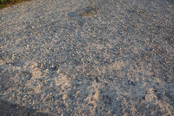 Gravel texture background with fine stones and sand under soft lighting, offering natural