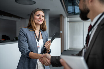 Businesswoman shaking hands with businessman at conference, making new business relationships