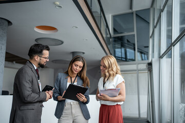 Businesspeople discussing notes on clipboard in office building