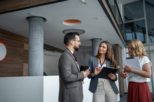 Businesspeople discussing work using digital tablet and clipboard in office lobby - Powered by Adobe