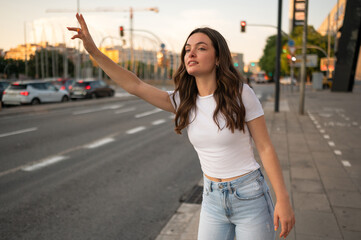 Young woman hailing taxi cab in a city street