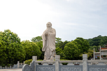 Confucius Statue Surrounded by Lush Green Trees in a Courtyard