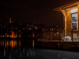Night view of illuminated waterfront with mosque and city lights reflecting on calm water in...