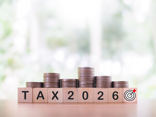 Wooden blocks with the word TAX, Number 2026 and stack of coins. The concept of prepare to pay tax in year 2026