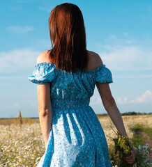 Young woman smiling while smelling daisies in field. Concept of peace and contentment. Summer bliss forever captured in this frame. vertical