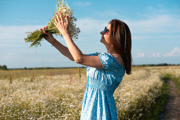 Young woman smiling while smelling daisies in field. Concept of peace and contentment. Summer bliss forever captured in this frame.