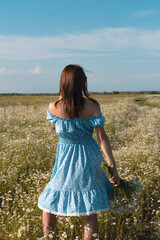 Young woman smiling while smelling daisies in field. Concept of peace and contentment. Summer bliss forever captured in this frame. vertical