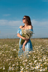 Young woman smiling while smelling daisies in field. Concept of peace and contentment. Summer bliss forever captured in this frame. vertical