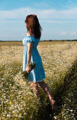 Young woman smiling while smelling daisies in field. Concept of peace and contentment. Summer bliss forever captured in this frame. vertical