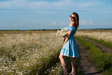 Young woman smiling while smelling daisies in field. Concept of peace and contentment. Summer bliss forever captured in this frame.
