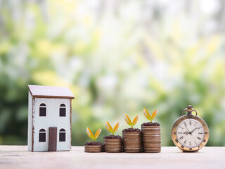 Vintage watch, Miniature house and plants growing up on stack of coins. The concept of saving money for house, Property investment, House mortgage, Real estate.