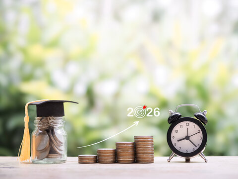 Glass bottle with graduation hat, Black alarm clock and stack of coins. The concept of saving money and manage time for education, student loan, scholarship, tuition fees in year 2026 - Powered by Adobe