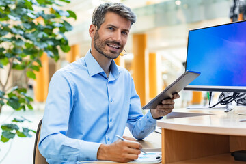 Portrait of successful businessman office worker looking camera holding tablet computer in hands,...
