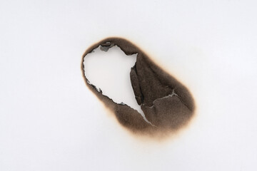 Burnt hole isolated on white paper. burns borders paper close up. Paper burn black stain mark close up.