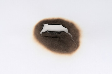Burnt hole isolated on white paper. burns borders paper close up. Paper burn black stain mark close up.