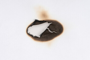 Burnt hole isolated on white paper. burns borders paper close up. Paper burn black stain mark close up.
