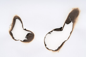 Burnt hole isolated on white paper. burns borders paper close up. Paper burn black stain mark close...