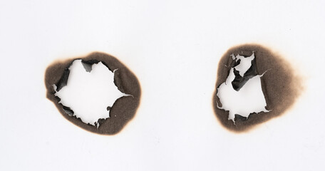 Burnt hole isolated on white paper. burns borders paper close up. Paper burn black stain mark close up.