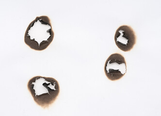 Burnt hole isolated on white paper. burns borders paper close up. Paper burn black stain mark close up.