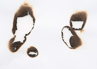 Burnt hole isolated on white paper. burns borders paper close up. Paper burn black stain mark close...