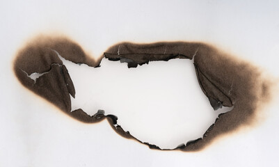 Burnt hole isolated on white paper. burns borders paper close up. Paper burn black stain mark close up.