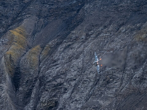 Swiss Air Force F/A-18 jet performing high-speed maneuver with afterburners against rugged Alpine mountain backdrop