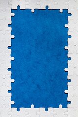Framing in the form of a rectangle, made of a white jigsaw puzzle. Frame text and jigsaw puzzles. Frame made of jigsaw puzzle pieces on blue background.