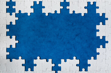 Framing in the form of a rectangle, made of a white jigsaw puzzle. Frame text and jigsaw puzzles. Frame made of jigsaw puzzle pieces on blue background.