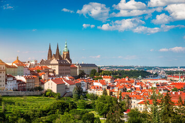 Obraz premium View of Prague featuring historic castle and vibrant rooftops on a sunny day in summer. Aerial view of Prague, Charles Bridge over Vltava river in Prague, Czechia. Old Town of Prague, Czech Republic.