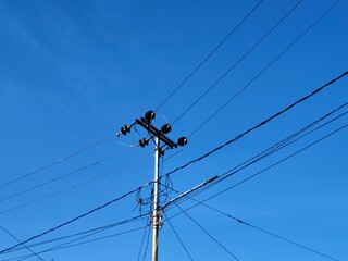 Tall Utility Pole with Wires Against Bright Blue Sky Backdrop