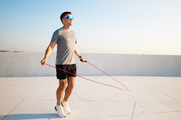 Jumping rope on a sunny rooftop in the heart of the city at sunset