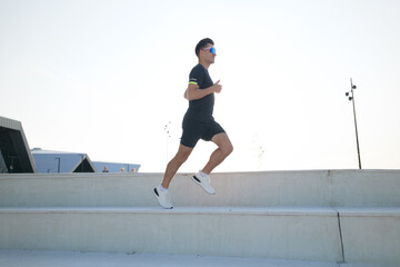 Runner ascends stairs energetically under a clear sky during daylight hours