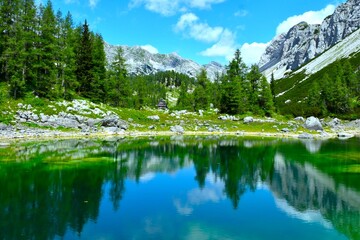 View of Dvojno jezero at Triglav lakes valley with mountains above the cottage and larch forest and...