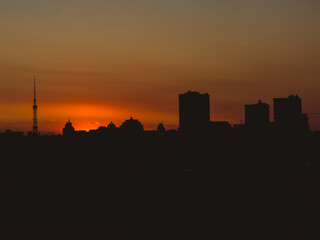 Dramatic urban skyline silhouette against a fiery sunset