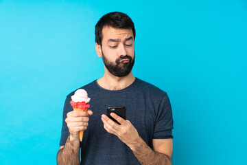 Young man with a cornet ice cream over isolated blue background thinking and sending a message