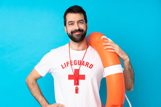 Lifeguard man over isolated blue background posing with arms at hip and smiling - Powered by Adobe