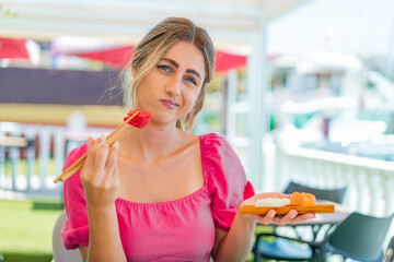 Young blonde woman holding sashimi at outdoors